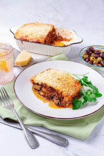 Moussaka served with olives, in a bright kitchen setting, homemade, no people