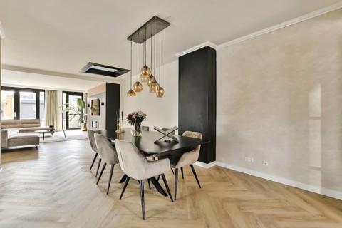 A stylish dining space featuring a wooden table, elegant pendant lighting, and a cozy sofa area.