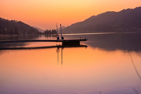 Footbridge juts into the lake, orange sky at sunset, quiet atmosphere, Großer Alpsee, Immenstadt im
