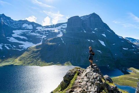 Hiker standing on a rock, view of mountain landscape and lake Giklingdalsvatnet, Flatvaddalen high