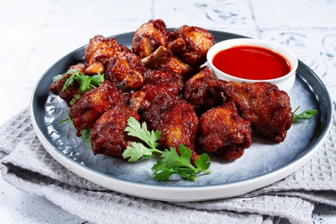 Crispy pieces of fried chicken, on a plate with sauce and herbs, in a modern kitchen environment,