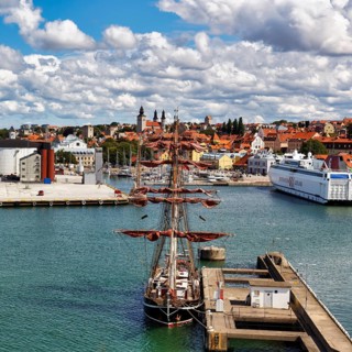 Historic tall ship and ferry in the harbor, city fortifications and old town of Visby, Gotland,