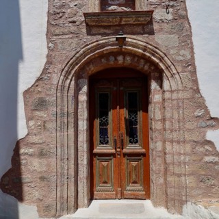Taxiarchis, Church of the Archangel, rustic wooden door in stone arch as the entrance to a historic