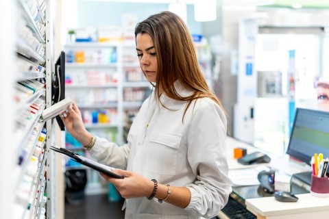 Pharmacist checking stock, organizing medication on shelves in a modern pharmacy, representing