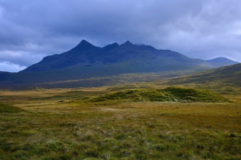 Rolling meadows in front of a massive mountain under dark clouds, Sligachan, Isle of Skye,