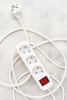 Power strip with multiple sockets and a switch in a cluttered setup on a textured surface during