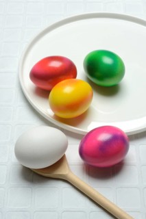 Coloured eggs on a plate and uncoloured eggs on a spoon, Easter celebration