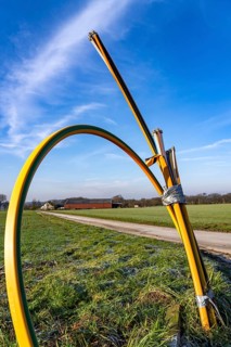 Fibre optic connection, empty conduits protrude from the ground along a dirt track, into which the