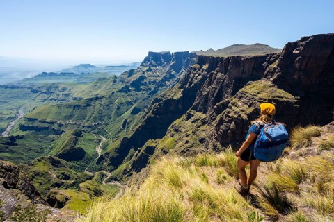 Young hiker looking at the impressive mountains and cliffs of the Drakensberg Mountains, hiking
