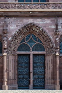 The main portal of Basel Cathedral with iron-clad wooden doors and richly decorated red sandstone