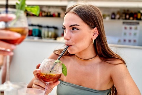 Friends relax at a beach side cafe, sipping colorful cocktails filled with fresh fruits and herbs.