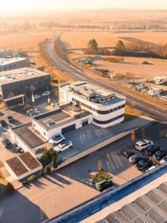 Modern style building in industrial area with surrounding streets and fields in sunny weather,