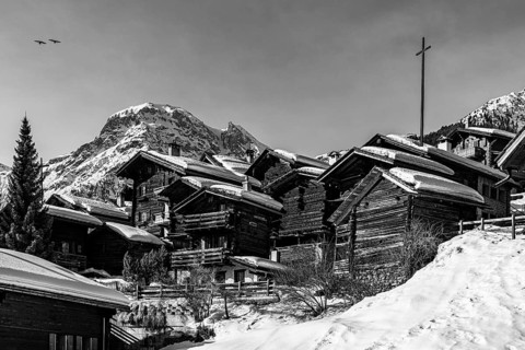 Snow-covered old farmhouses, large wooden cross, black and white photo, historic town center,