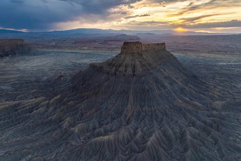 A breathtaking aerial view of a sunset gracing the unique and dramatic erosion of Factory Butte in