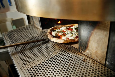 A freshly baked pizza out of an industrial oven, perfectly cooked with vibrant toppings