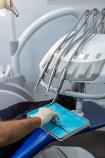 Close up of a dentist gloved hand reaching for a tool amidst advanced dental equipment. The image