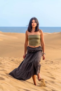 Young woman walking barefoot on the sand dunes of maspalomas with the ocean in the background