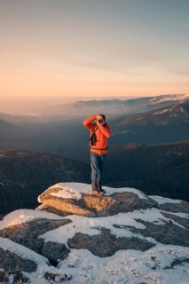 A person in vibrant attire photographs the snow-dusted peaks of Siete Picos, set against the serene