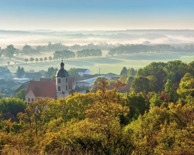 Morning atmosphere in the Saale valley near the village of Eulau with village church in autumn, fog