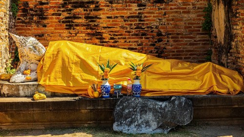 Reclining stone Buddha statue covered with yellow cloth, historic Buddhist temple complex,
