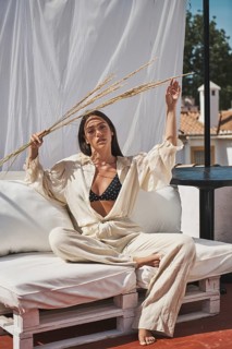A woman enjoys a summer day on a rooftop, dressed in light, casual clothing She holds dried