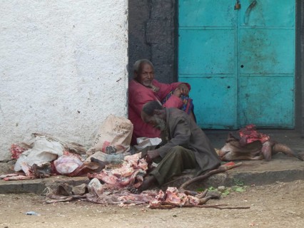 Two men cut up a cow (bos), meat and offal at the roadside in a central square in Harar, Ethiopia