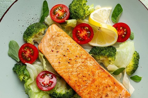 Grilled salmon fillet, with vegetables, broccoli, cherry, iceberg lettuce, spices and herbs,