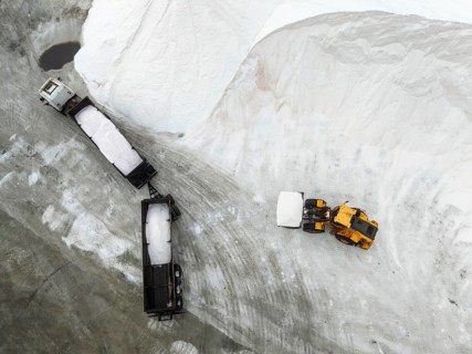Lorry and excavator at the salt heaps of the Walvis Bay Salt works. Aerial view. Drone shot. Walvis