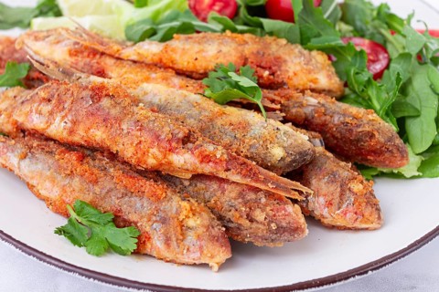 Fried crispy mullet fish, with fresh salad, on a plate with lime, no people