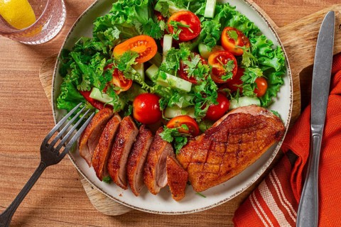 Delicious grilled duck breast served with fresh garden salad and cherry tomatoes at a rustic dining
