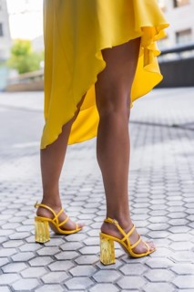 Vertical cropped photo of the sensual legs of a woman wearing yellow dress heels