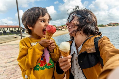Cheerful mother and child share a joyful selfie while enjoying ice cream cones on a sunny summer