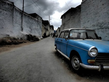 A blue old car, vintage car, stands in a deserted alley under cloudy sky, Gondar, Ethiopia