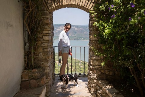 An Asian woman enjoys a sunny day with her dog in Castellar de la Frontera, Cadiz. Standing under a