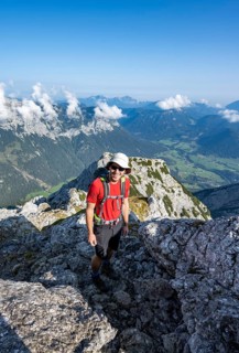 Mountaineer on a rocky mountain path with mountain panorama, mountain tour to the summit of the
