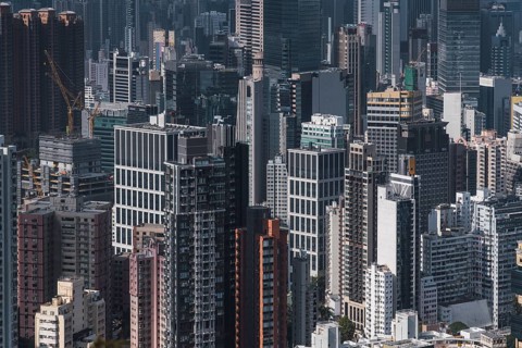 Aerial view of Hong Kong's bustling skyline showcases a dense cluster of modern skyscrapers,