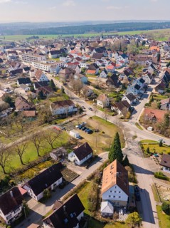 Houses with red roofs in a village, surrounded by streets and green areas, photographed from a