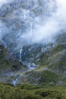 Mountain landscape with waterfalls and clouds on Lake Marian. Fiordland National Park, Southland