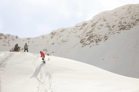 Two snowboarders gracefully glide down a pristine, snow-covered mountain, capturing the thrill of