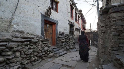 Narrow alley in a mountain village with stone walls and traditional house at dusk, one person walks