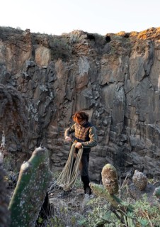 A climber prepares for a traditional climbing adventure on a rugged cliff side, surrounded by