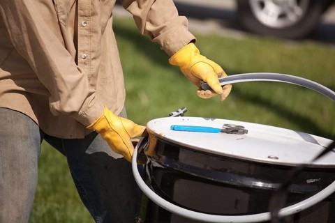 Utility Worker with Leather Gloves Opening or Sealing Oil Drum