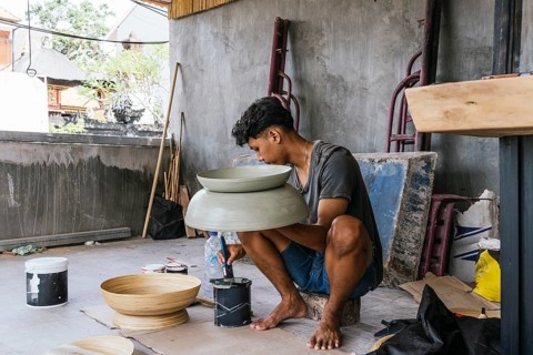 Balinese artist painting sculptures in a traditional setting, showcasing cultural craftsmanship.