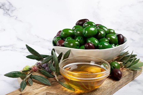 Chalkidiki olives, classic Greek green olives, in a bowl on a cutting board, top view, without