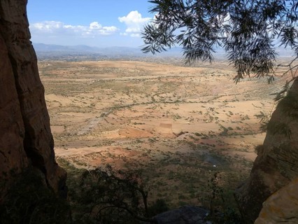 View from Abuna Yemata Guh rock church through trees to a wide valley and distant mountains,