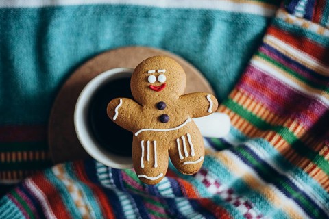 Charming gingerbread man cookie adorns a cup of coffee The vibrant patterned fabric beneath