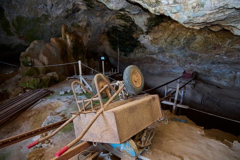 Rusty excavation cart standing in a cave on wooden platforms, museum, Charkadio Cave, dwarf