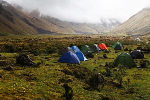 A group of colorful tents set up in a remote Andean valley at El Altar volcano, Ecuador, surrounded