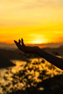 Woman's hand silhouette holding the setting sun at mount tapyas, coron island, philippines,