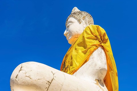 Stone Buddha statue decorated with yellow cloth, historic Buddhist temple complex, Ayutthaya,